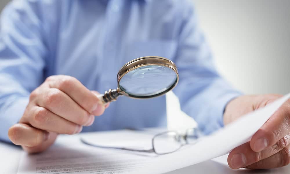 Businessman reading documents with magnifying glass concept for analyzing a finance agreement or legal contract