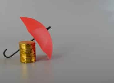 Red umbrella and the stack of coins. Keeping money safe. savings protection, Investment and capital insurance concept.