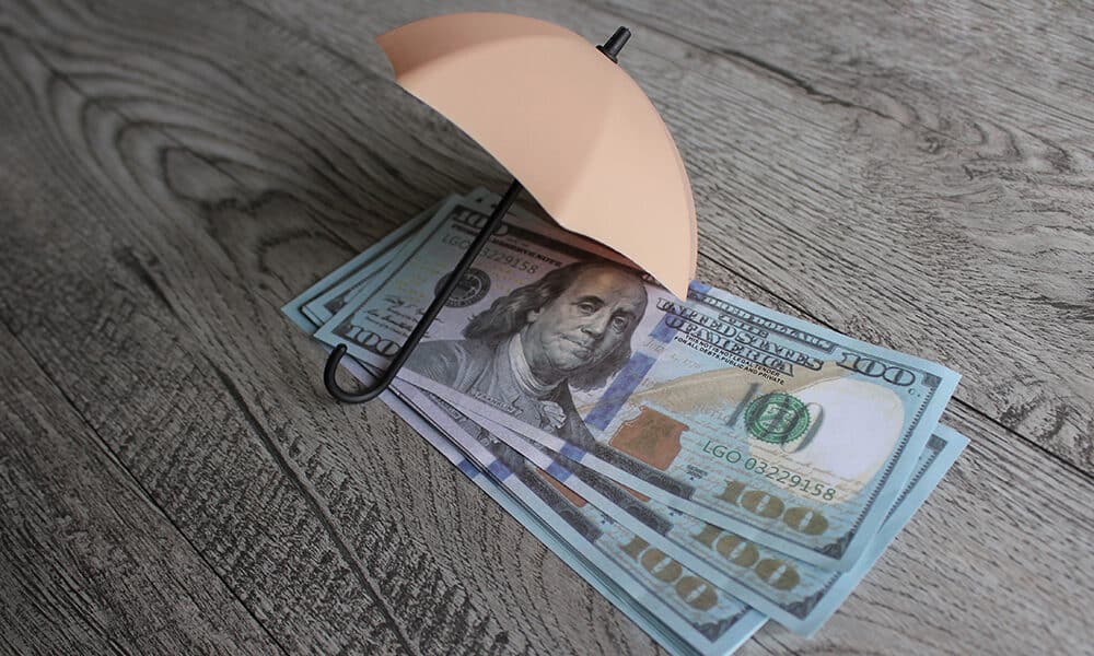 Stack of money and umbrella for protection with copy space. Financial safety and investment concept.