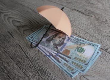 Stack of money and umbrella for protection with copy space. Financial safety and investment concept.