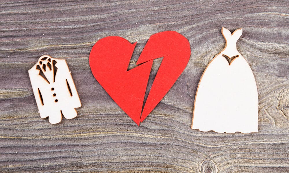 Divorce and canceling marriage concept. Broken heart and wedding dresses on wood.