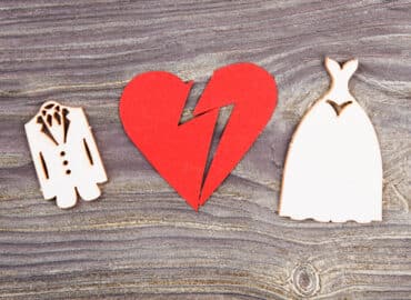 Divorce and canceling marriage concept. Broken heart and wedding dresses on wood.