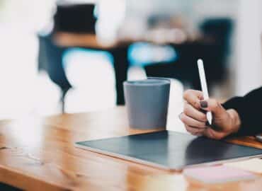 Close up Female hands drawing on digital tablet with electronic pen. Freelancer designer working remotely. Business working on laptop computer.